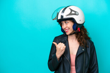 Young caucasian woman with a motorcycle helmet isolated on blue background pointing to the side to present a product