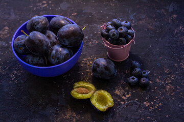 Ripe juicy plums in a bowl on a table. Summer fruits.