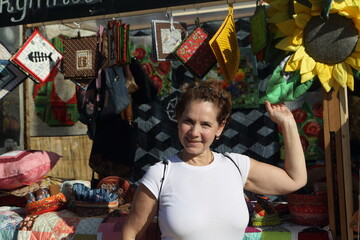 Woman at the fair chooses souvenirs and clothes - obrazy, fototapety, plakaty