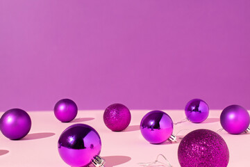 Christmas baubles with hard shadows isolated on velvet violet and pink background. Winter, new year or Christmas concept. Minimal holiday composition..