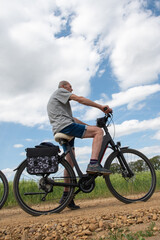 Fototapeta na wymiar middle-aged man on an electric bike against a sky with clouds, 