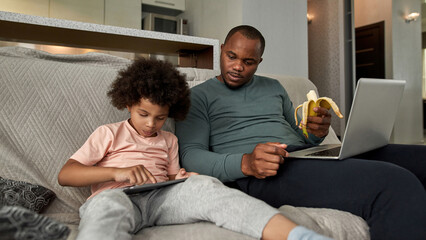 Father looking at little son using digital tablet