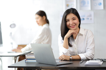 Portrait of a charming Asian business woman working on a laptop in the office.