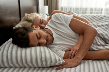 Side view of young multiethnic couple sleep on bed