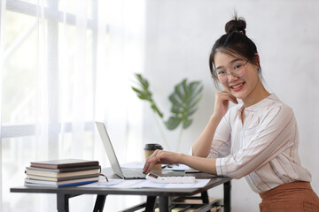 Portrait of a young Asian woman in the secretary's office smiling and looking happy.