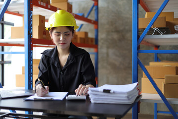 Small warehouse worker working with a laptop is checking the inventory. Entrepreneurs start-up e-commerce businesses working in the office.