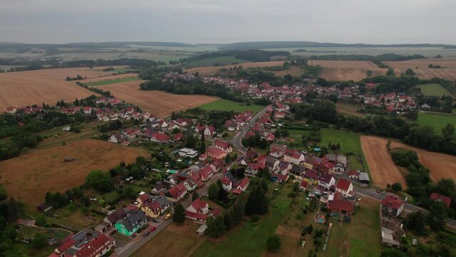 Aer ial view of a German village surrounded by meadows, farmland and forest in Germany.