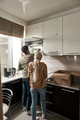 Man packing cooking utensils in box with wife