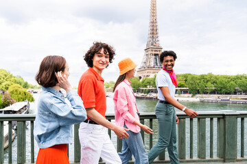 Multiethnic group of young happy teens friends bonding and having fun while visiting Eiffel Tower area in Paris, France