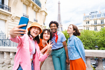 Multiethnic group of young happy teens friends bonding and having fun while visiting Eiffel Tower area in Paris, France