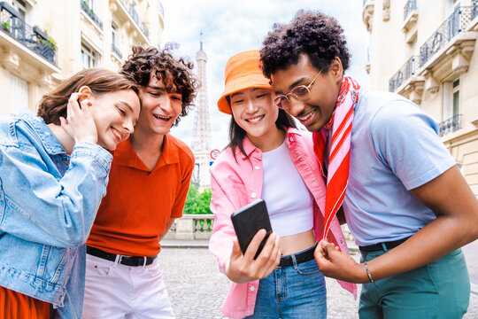 Multiethnic group of young happy teens friends bonding and having fun while visiting Eiffel Tower area in Paris, France