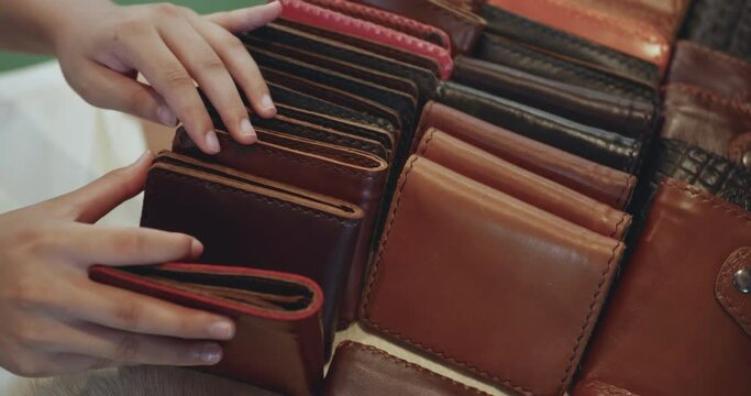 Woman's hand choosing a leather wallet in the store
