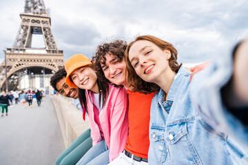 Multiethnic group of young happy teens friends bonding and having fun while visiting Eiffel Tower area in Paris, France - obrazy, fototapety, plakaty