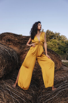 Beautiful Woman With Dark Hair In Elegant Yellow Dress Posing In The  Hayloft On Sunset