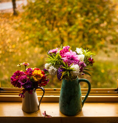 autumn windowsill. Bouquet of autumn flowers, and little kitten against beautiful autumn view