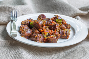 rougail de saucisses fumées dans une assiette blanche, spécialité culinaire réunionnaise 