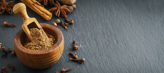Ground cloves in wooden bowl on slate background with copy space