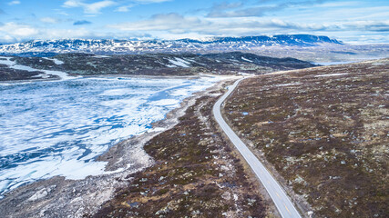 Spectacular aerial view of the Hardangervidda mountain road and area with snow and melting ice on the lakes