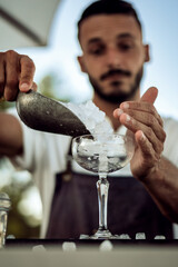 male person working as a bartender fills glass with ice