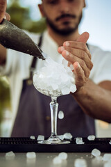 male person working as a bartender fills glass with ice
