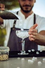 male person working as a bartender fills glass with ice