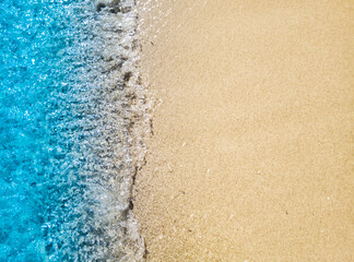 Fototapeta na wymiar Beautiful beach background with clear and foamy blue sea water waves and clean white sandy beach. 