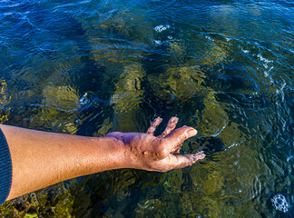 Hand of an asian man touching the water in the ocean. World water concept, clean water environment, environmental health, natural sea water cleanliness concept. World Oceans Day. Marine pollution 