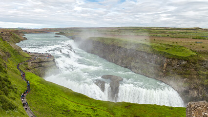a big crowd in front of the Gulfoss waterfall in  Haukadalur, Iceland