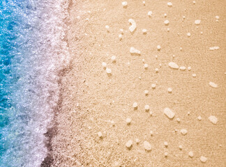 Beautiful beach background with clear and foamy blue sea water waves and clean white sandy beach. 