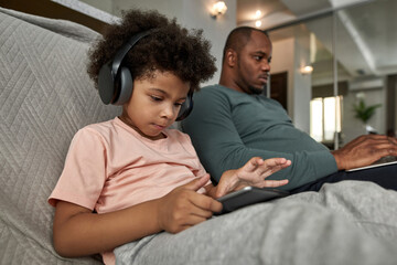 Son use digital tablet while father type on laptop