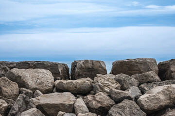 Horizontal background of grey stone boulders (bottom) with a level horizon line and blue clouds above.  Room for text.