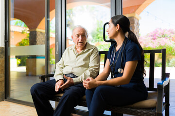 Female nurse and mature elder man having a conversation at the retirement home