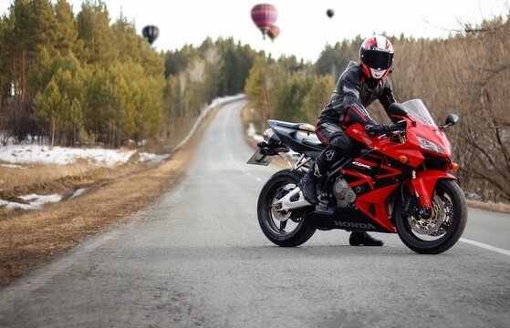 KRASNOYARSK, RUSSIA - April 23, 2019: Beautiful motorcyclist in full gear and helmet on a red and black Honda 2005 CBR 600 RR (PC37)