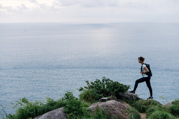 Athletes running on a forest path against the sea in the background. Looking at the clock. Health concept jogging fitness woman.