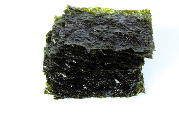 Seasoned seaweed snack. Algae sheets stacked in a pile on white background. © Owl_photographer