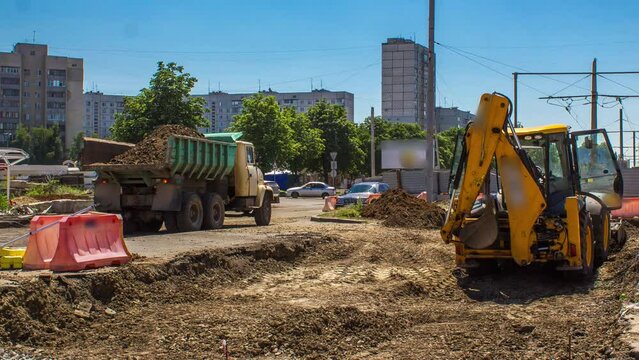Industrial excavator diging ground and loading into a truck timelapse on a road construction site. Preparation to reconstruction of tram tracks in a big city