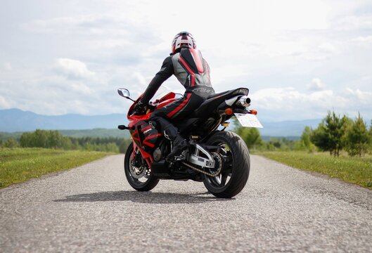 KRASNOYARSK, RUSSIA - May 31, 2019: Beautiful motorcyclist in full gear and helmet on a red and black Honda 2005 CBR 600 RR (PC37)