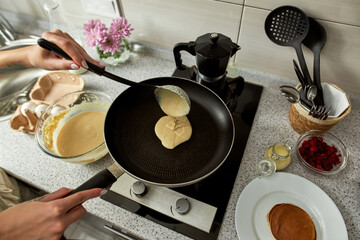 Woman pouring dough on pan on stove during cooking