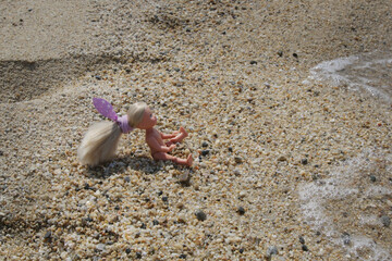 Little plastic doll on the sand beach	