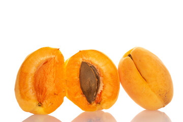 One whole and two halves of pineapple apricot with a seed, macro, isolated on white.