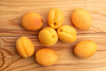 Several organic yellow pineapple apricots, close-up, on a white wooden table, top view.