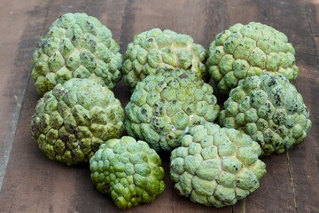 Custard apple kept for sale in the market. Healthy raw fruit. Closeup of food in the wooden table.