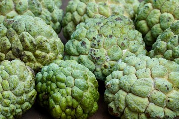 Custard apple kept for sale in the market. Healthy raw fruit. Closeup of food in the wooden table.