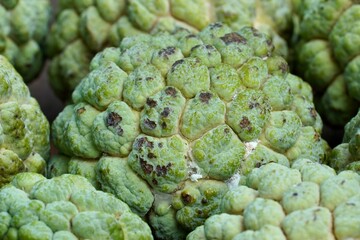 Custard apple kept for sale in the market. Healthy raw fruit. Closeup of food in the wooden table.