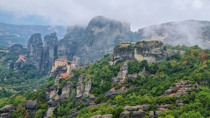Fototapeta na wymiar Scenic view of Holy Monastery of St Nicholas Anapafsas and Holy Monastery of Rousanos surrounded by fog on cloudy day, Kalambaka, Meteora, Thessaly, Greece, Europe. Landmark build on rock formations