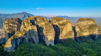 Fototapeta na wymiar Early morning aerial panoramic view during sunrise of the rock formation complex of Meteora in Kalambaka, Meteora, Thessaly, Greece, Europe. Sun on dramatic moss overgrown rock pinnacles of Meteora