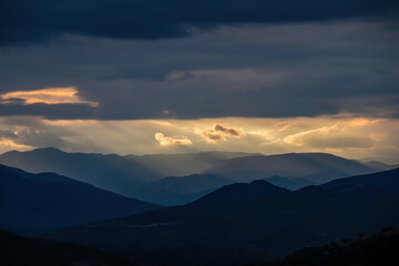 Panoramic view during sunset from Meteora rocks to Pindos mountains, the biggest mountain range of Greece, Thessaly district, Greece, Europe. Soft sun beam through clouds reaching the summit tops