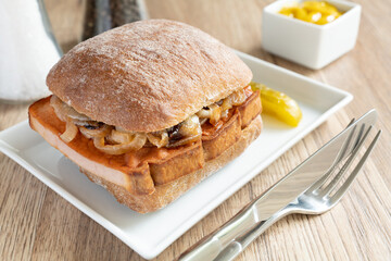 Dunkles Brötchen mit Leberkäse und geschmorten Zwiebeln.