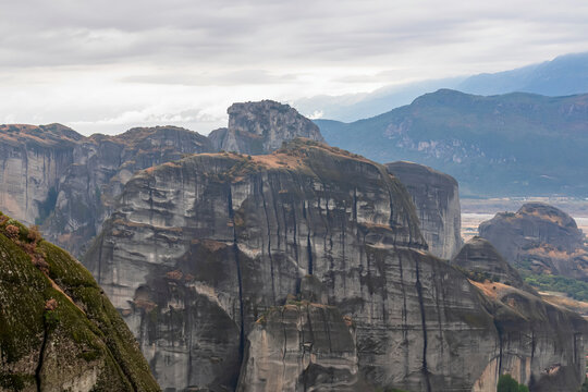 Panoramic view of unique rock formations near Holy Monastery of Varlaam on cloudy foggy day in Kalambaka, Meteora, Thessaly, Greece, Europe. Rocks overgrown with green moss creating moody atmosphere © Chris