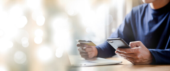 Man holding credit card and using smartphone at home online shopping ecommerce internet banking spend money work from home concept.